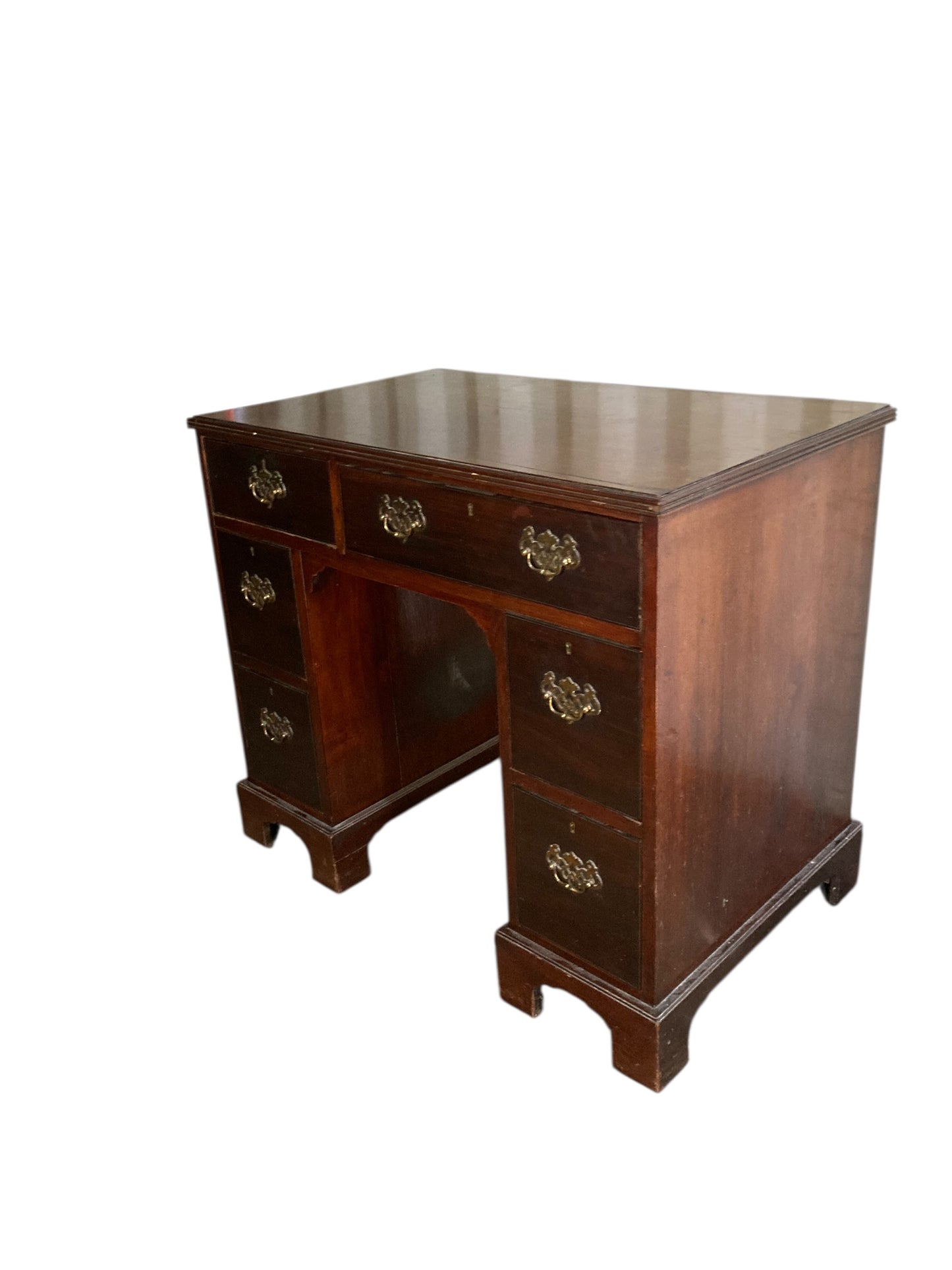 A George III crossbanded mahogany kneehole desk of six drawers with gilt handles