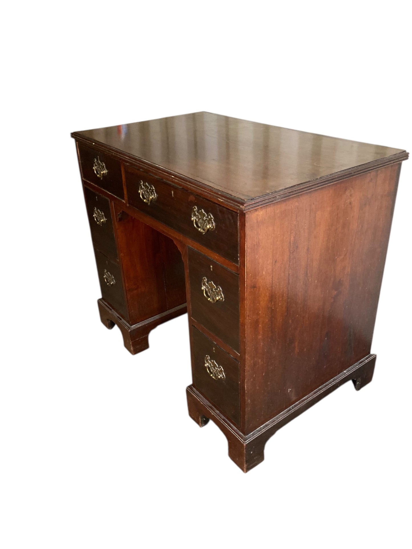 A George III crossbanded mahogany kneehole desk of six drawers with gilt handles