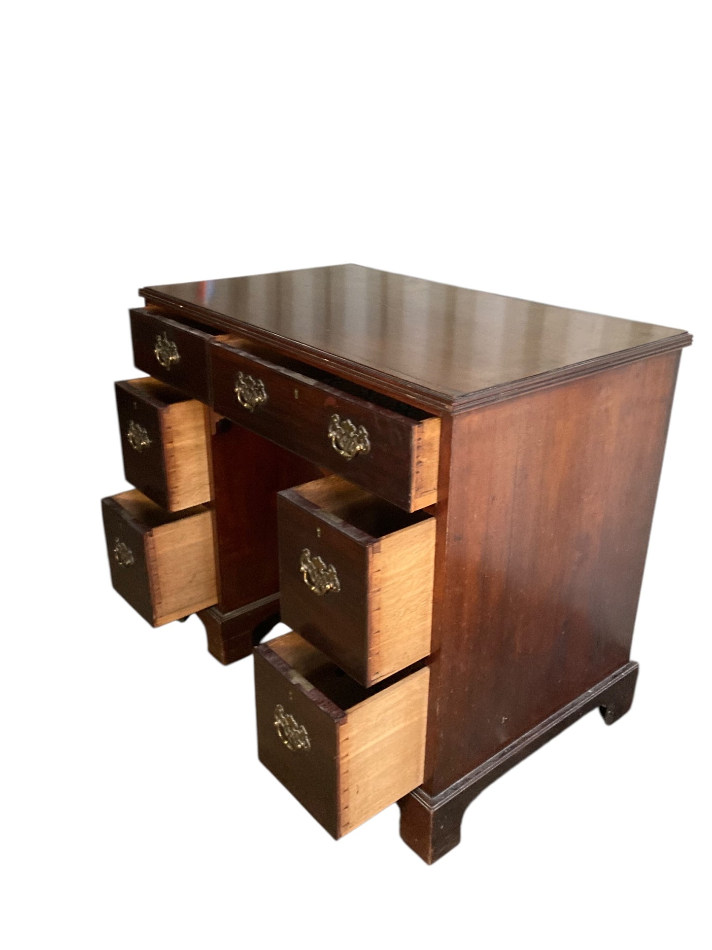 A George III crossbanded mahogany kneehole desk of six drawers with gilt handles