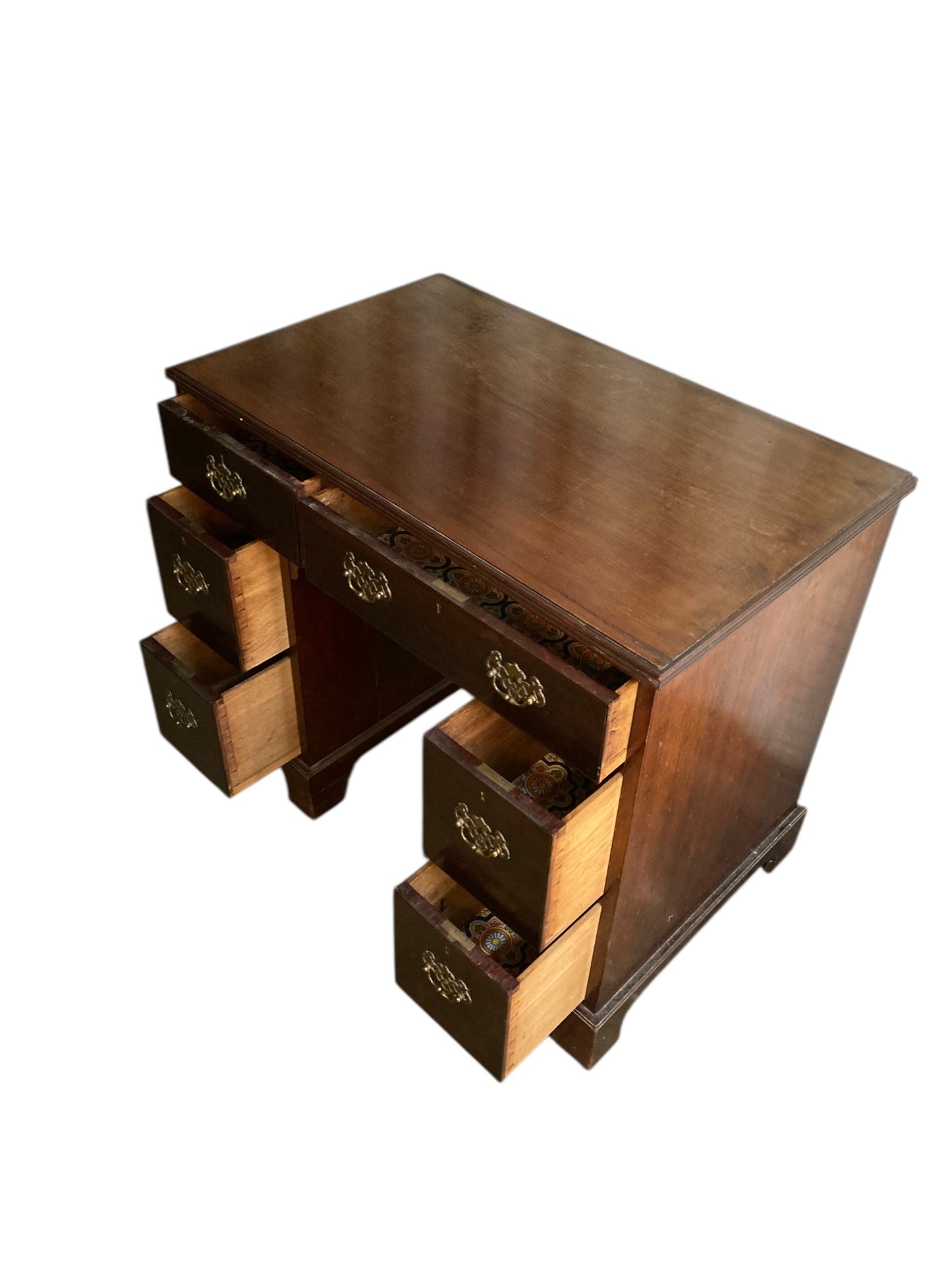 A George III crossbanded mahogany kneehole desk of six drawers with gilt handles