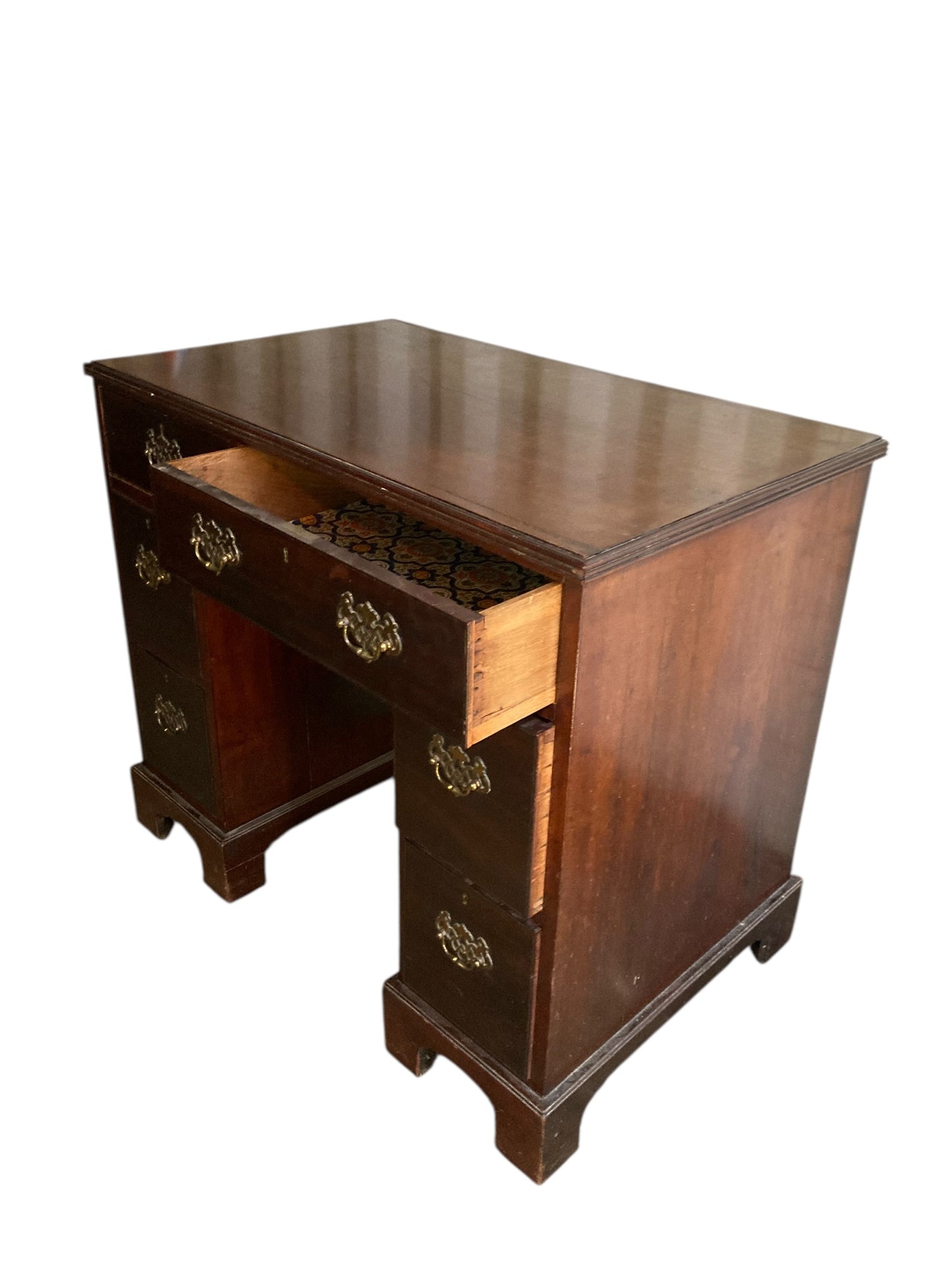 A George III crossbanded mahogany kneehole desk of six drawers with gilt handles