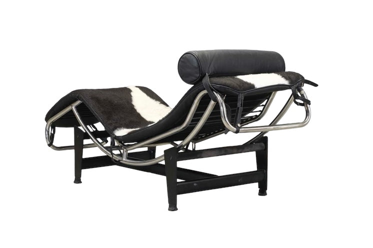 An 'LC4'  Le Corbusier Style chaise longue,upholstered in pony hide and with a black leather neck roll cushion to the chromium-plated tubular frame,