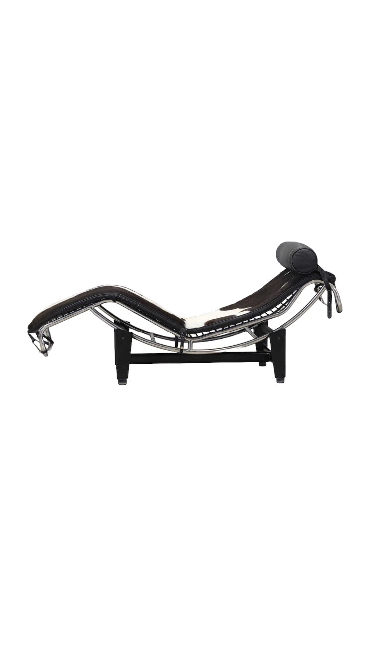 An 'LC4'  Le Corbusier Style chaise longue,upholstered in pony hide and with a black leather neck roll cushion to the chromium-plated tubular frame,